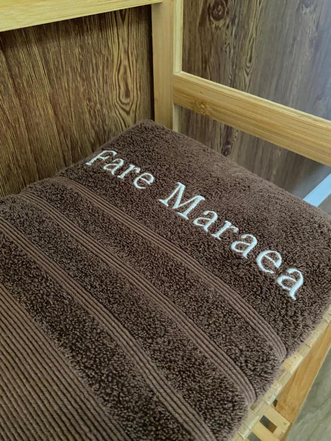 Brown towel embroidered Fare Maraea rests on wooden chair at pet-friendly Fare Maraea in Vaiare.