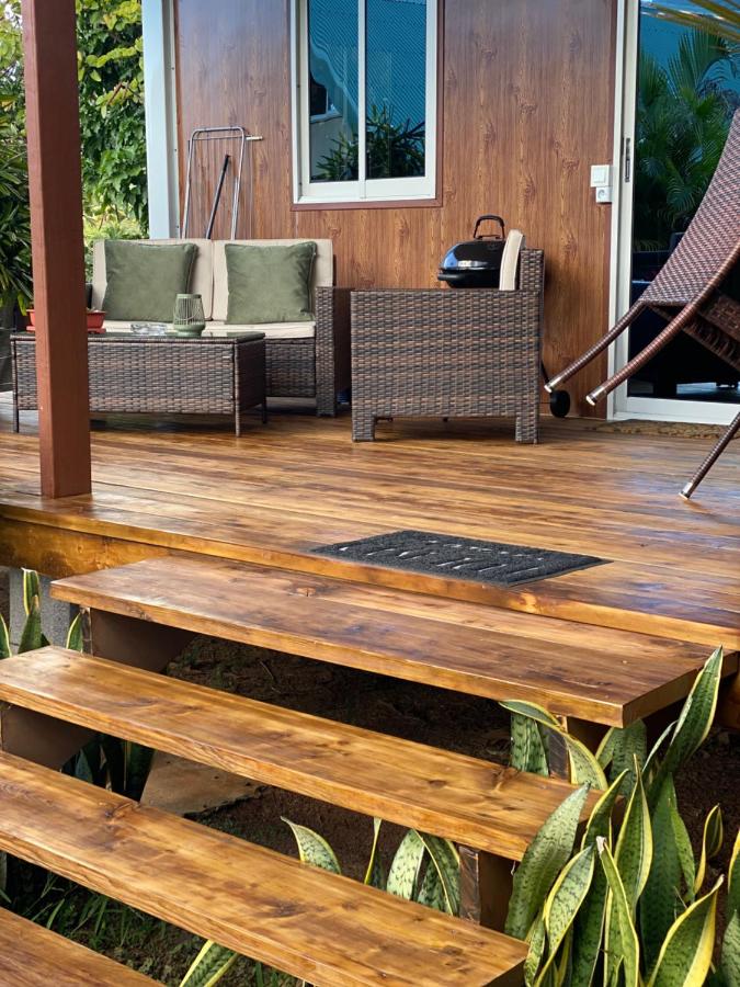 A brown wicker chair with green cushions sits on the wooden deck at dog-friendly Fare Maraea in Vaiare.