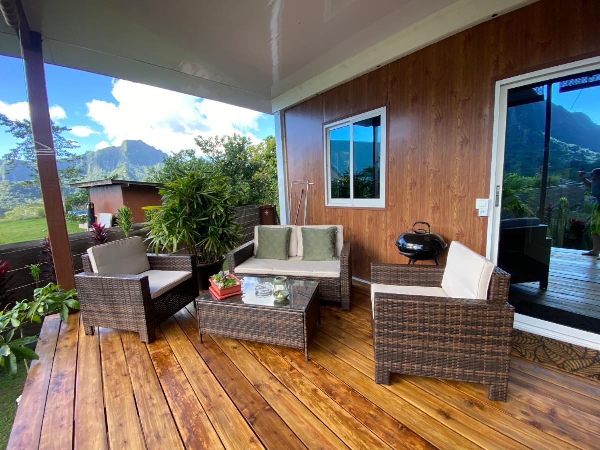 Wicker patio set with beige cushions and green pillows sits at dog-friendly Fare Maraea in Vaiare.