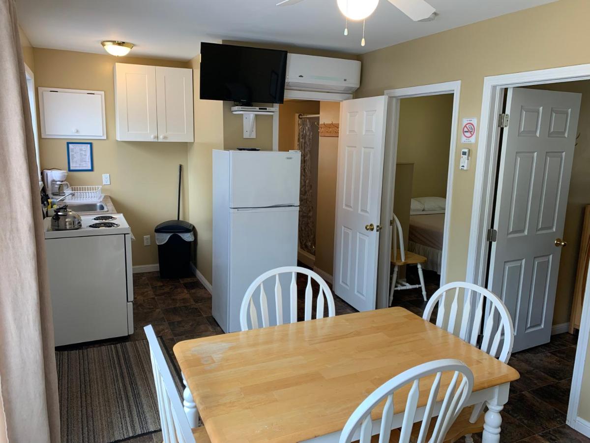 White wooden dining table with four white chairs sits at pet-friendly Wu Wu's Cabins in Wasaga Beach, ON.