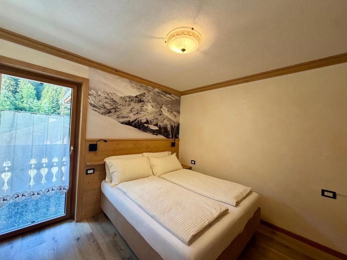 Double bed with white linens and wooden headboard sits against wall at pet-friendly Rosengarden Alpine Residence in Valdidentro.