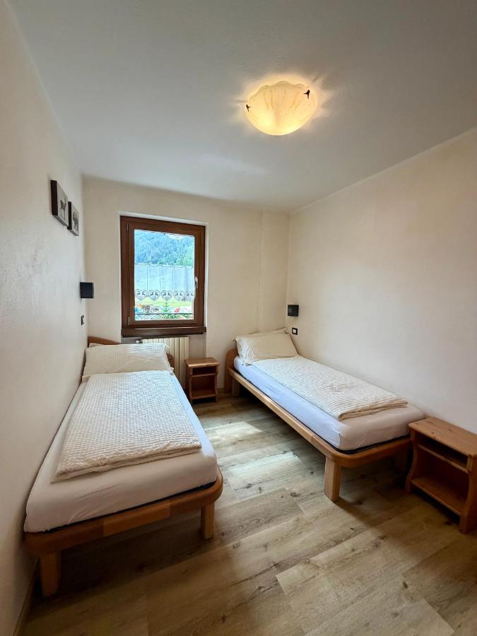 Two single beds with white linens and wooden frames are placed at pet-friendly Rosengarden Alpine Residence in Valdidentro.