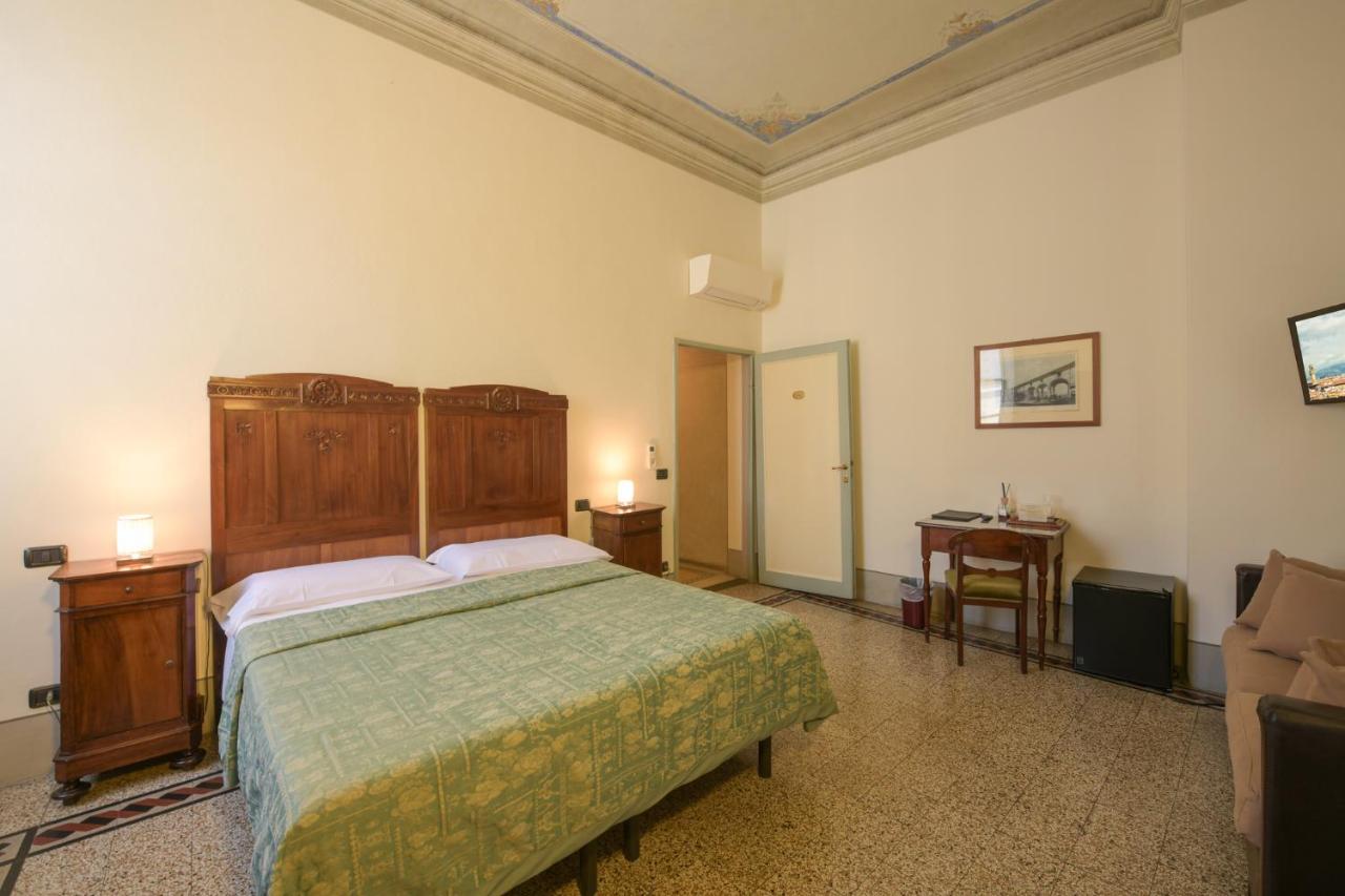 Double bed with green patterned cover and carved wooden headboard sits at dog-friendly Casa Rovai Guest House in Florence.