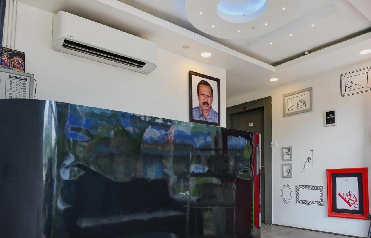Portrait of man in blue shirt hangs by black desk at dog-friendly Town House HI5 Aditya International in Bhubaneshwar.