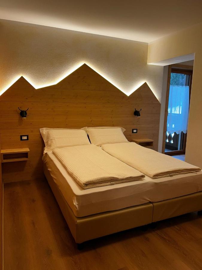 Beige beds with white duvets and wooden headboard sit at dog-friendly Rosengarden Alpine Residence in Valdidentro.