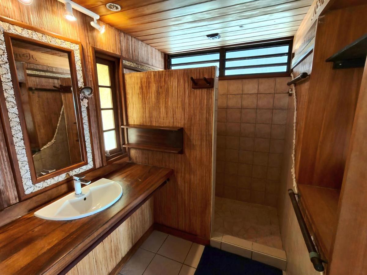 Wood-paneled bathroom with white sink sits at dog-friendly Vahaui Paradis in Avatoru.