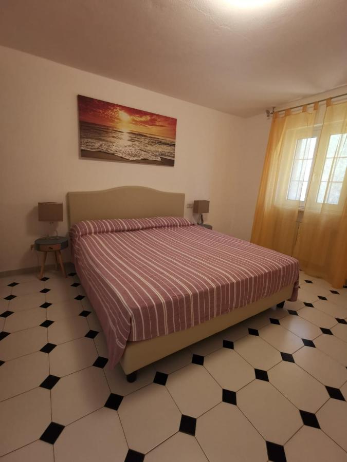 Beige upholstered bed with pink striped cover sits at dog-friendly Case Sole E Luna in Porto Azzurro.