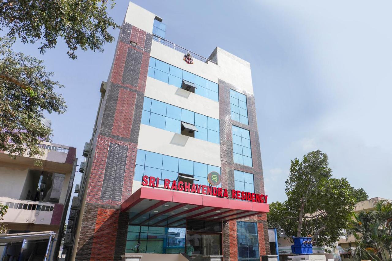 Tall white and red building with blue windows stands at pet-friendly Hotel O Raghavendra Residency in Warangal.