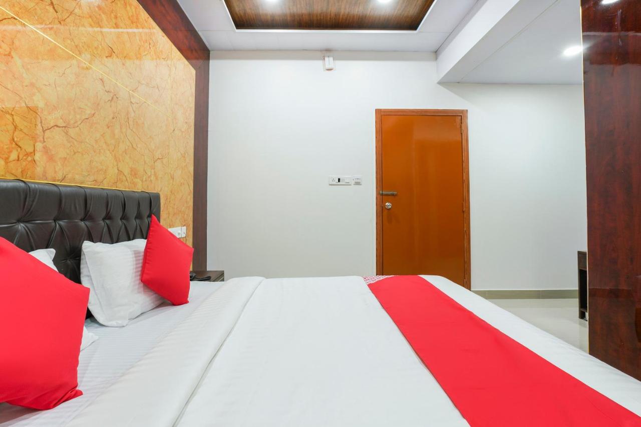 White bed with red pillows and dark tufted headboard occupies room at dog-friendly Hotel O Raghavendra Residency in Warangal.