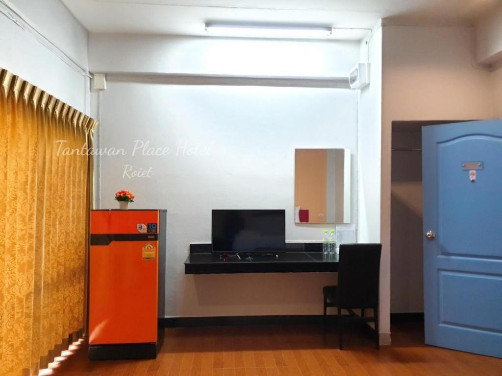 Orange mini refrigerator with red flower pot sits beside black desk at pet-friendly Tantawan Place in Roi Et.