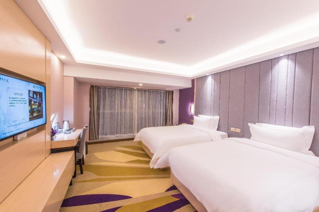 Two white beds with purple headboards sit at dog-friendly Lavande HotelsWuhan Zhuyeshan Metro Station in Zhanjiaji.