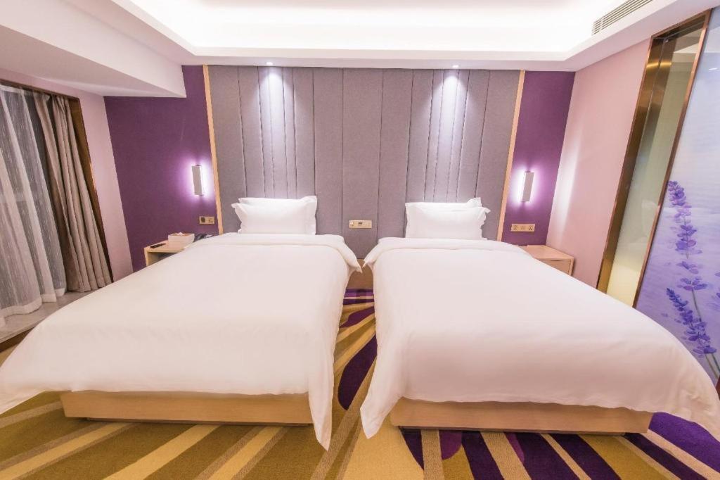 Two white beds with purple headboard are positioned at dog-friendly Lavande HotelsWuhan Zhuyeshan Metro Station in Zhanjiaji.