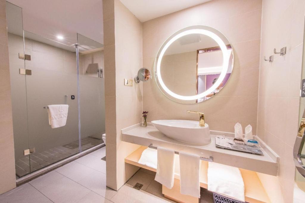 White towel embroidered with logo hangs on glass shower door at dog-friendly Lavande HotelsWuhan Zhuyeshan Metro Station in Zhanjiaji.