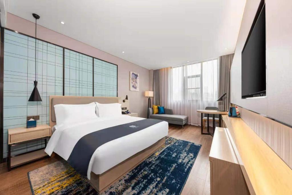 Bed with white linens and navy runner sits at dog-friendly Echarm Hotel Wuhan Plaza Wansongyuan in Wuhan.