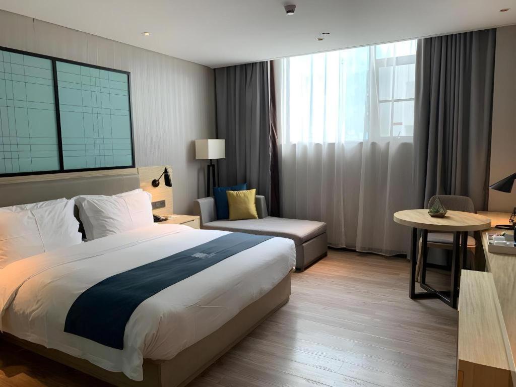 White bed with navy runner sits at pet-friendly Echarm Hotel Wuhan Plaza Wansongyuan in Wuhan.