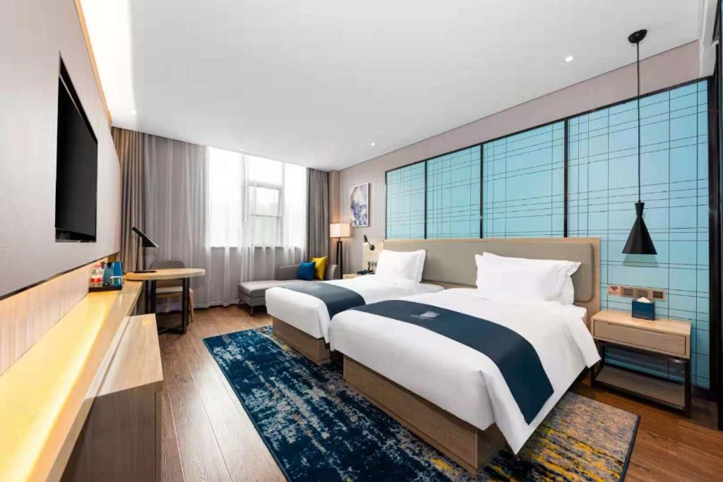 Two white beds with navy blue runners sit at pet-friendly Echarm Hotel Wuhan Plaza Wansongyuan in Wuhan.