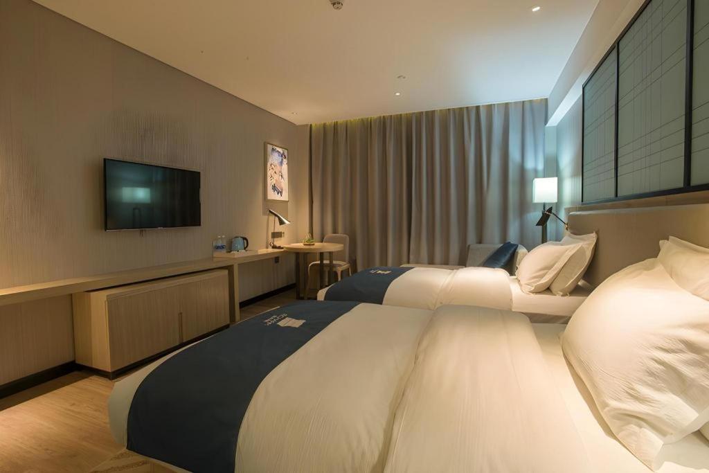 Two white beds with navy runners sit at pet-friendly Echarm Hotel Wuhan Plaza Wansongyuan in Wuhan.