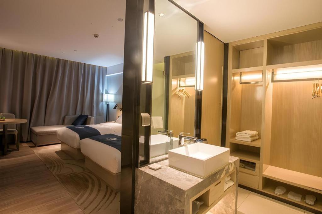Twin beds with white linens and navy runners sit at pet-friendly Echarm Hotel Wuhan Plaza Wansongyuan in Wuhan.