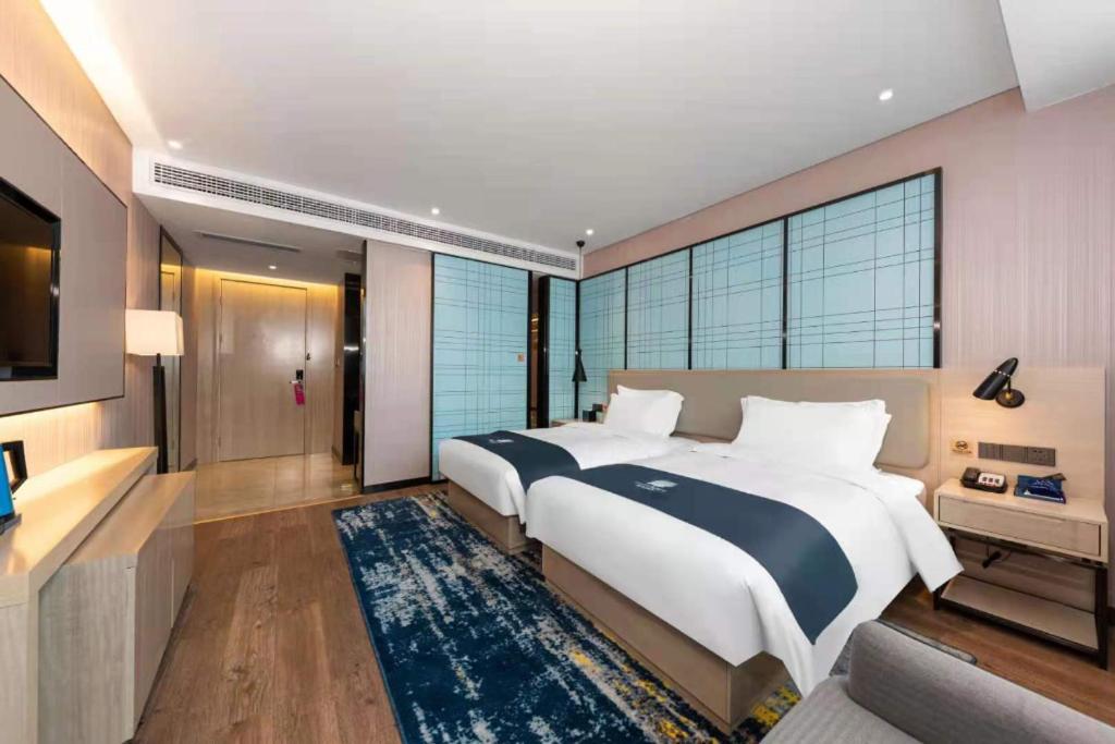 Two white beds with navy runners are positioned at pet-friendly Echarm Hotel Wuhan Plaza Wansongyuan in Wuhan.