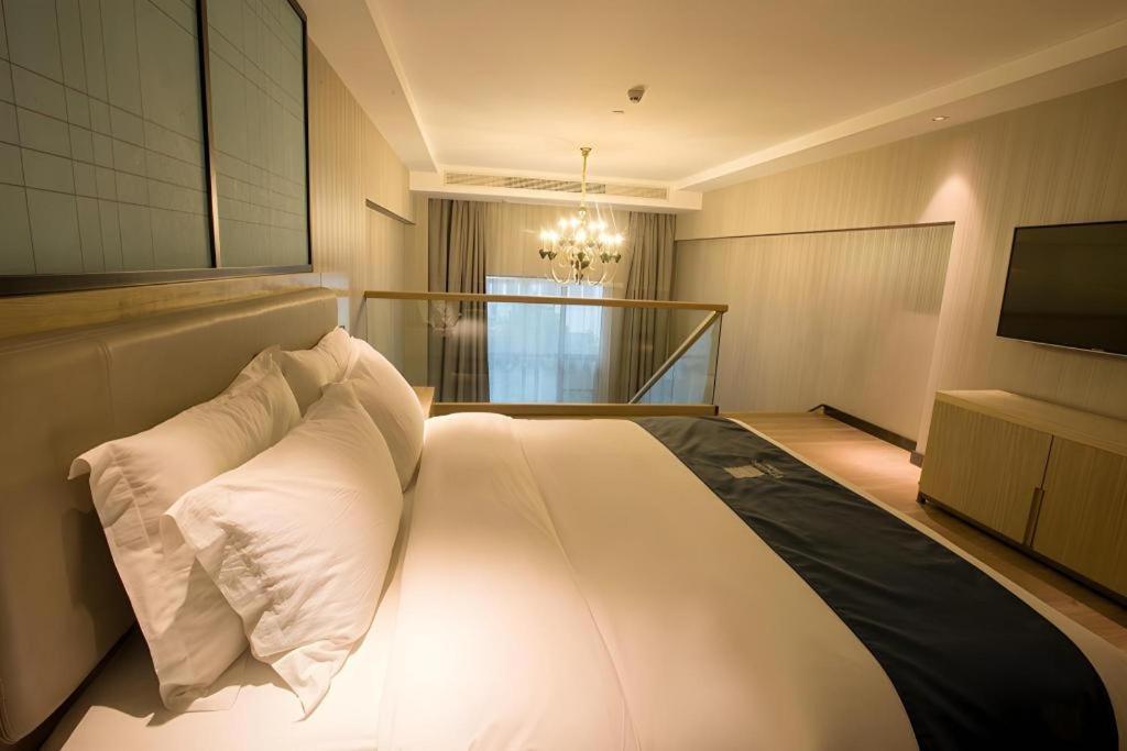 The king bed with white linens and dark runner sits at dog-friendly Echarm Hotel Wuhan Plaza Wansongyuan in Wuhan.