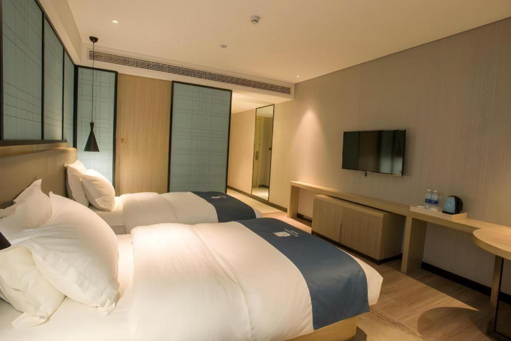 Two white beds with blue runners are positioned at dog-friendly Echarm Hotel Wuhan Plaza Wansongyuan in Wuhan.