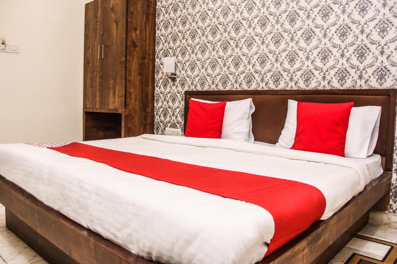 The bed with white sheets, red runner and red pillows sits at pet-friendly Collection O Hotel Chawla in Jaipur.