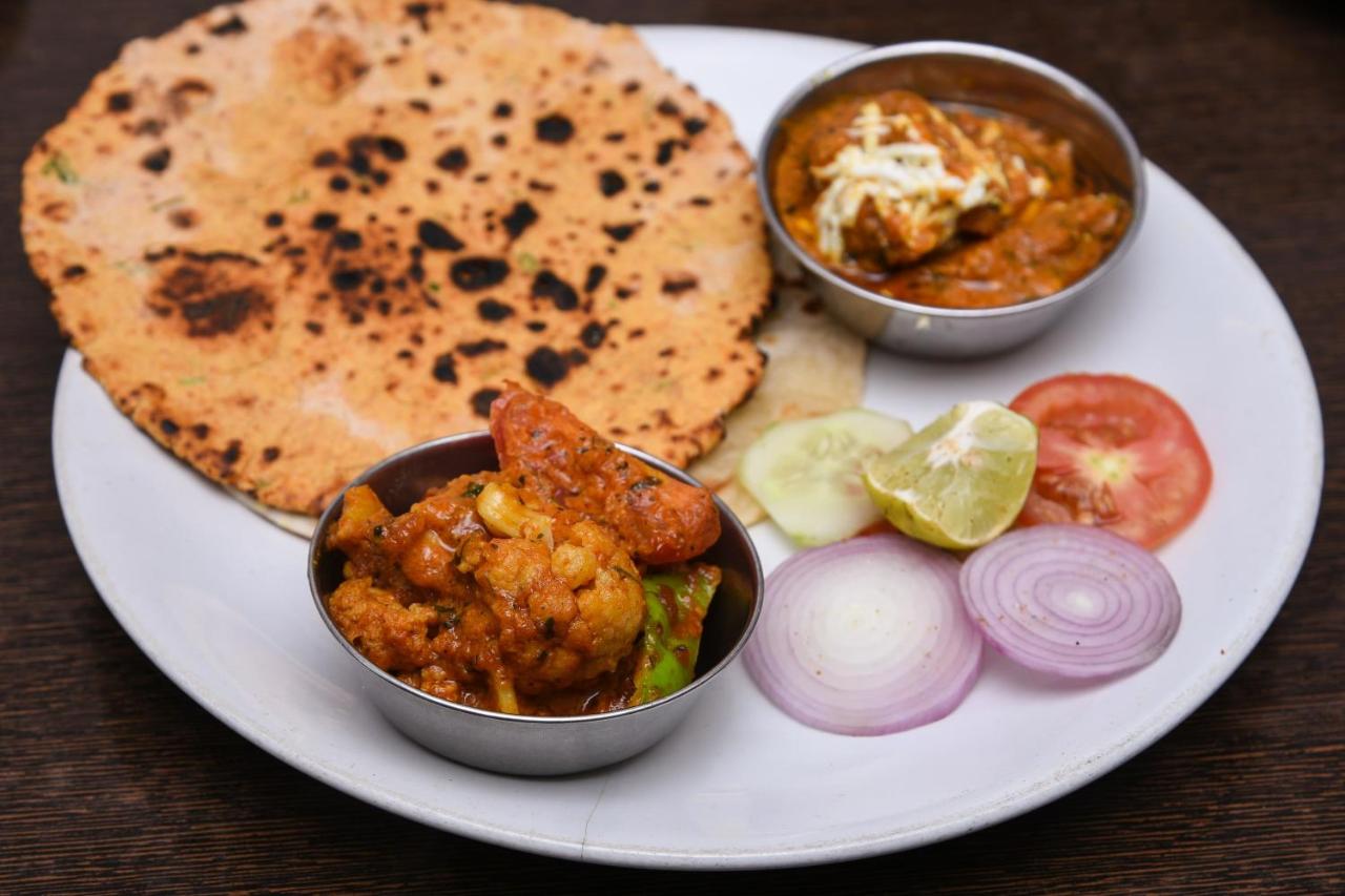 Plate with charred flatbread and steel bowls of curry sits at dog-friendly Hotel O Morgan in Bani Park.