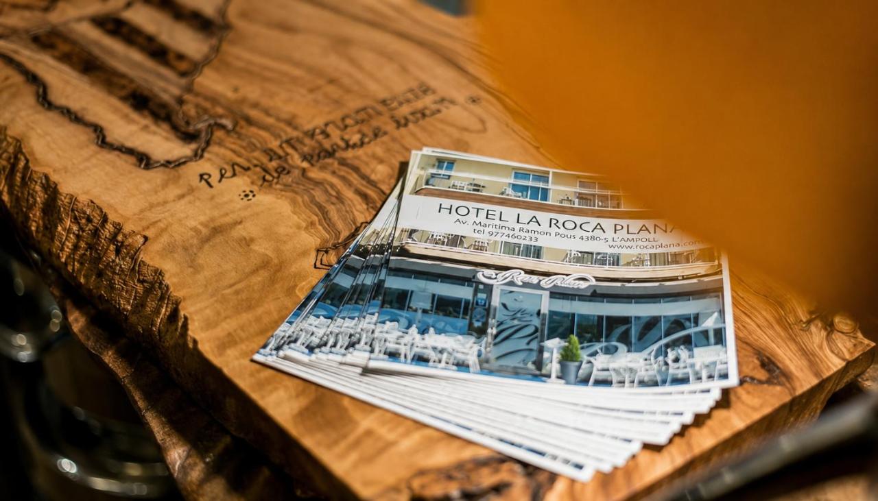 Stack of glossy blue-and-white hotel brochures sits on wooden slab at dog-friendly Hotel Roca Plana in L'Ampolla.