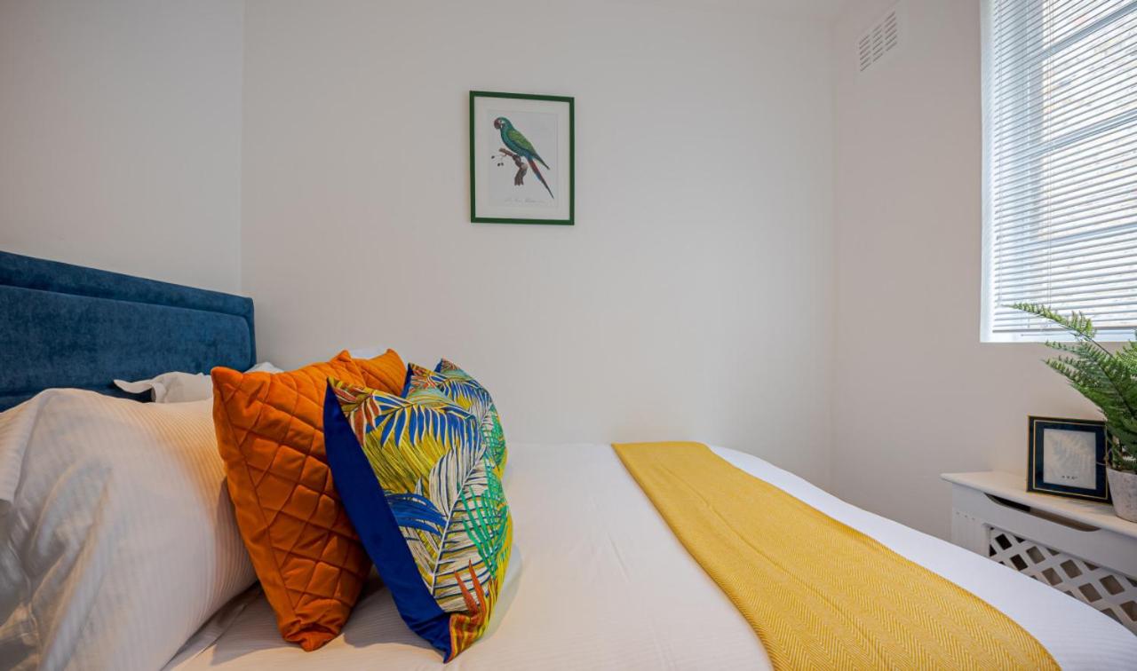 Blue bed with orange pillows sits at dog-friendly Stylish 3Bd House in Fulham - Close to Tube Station in London.