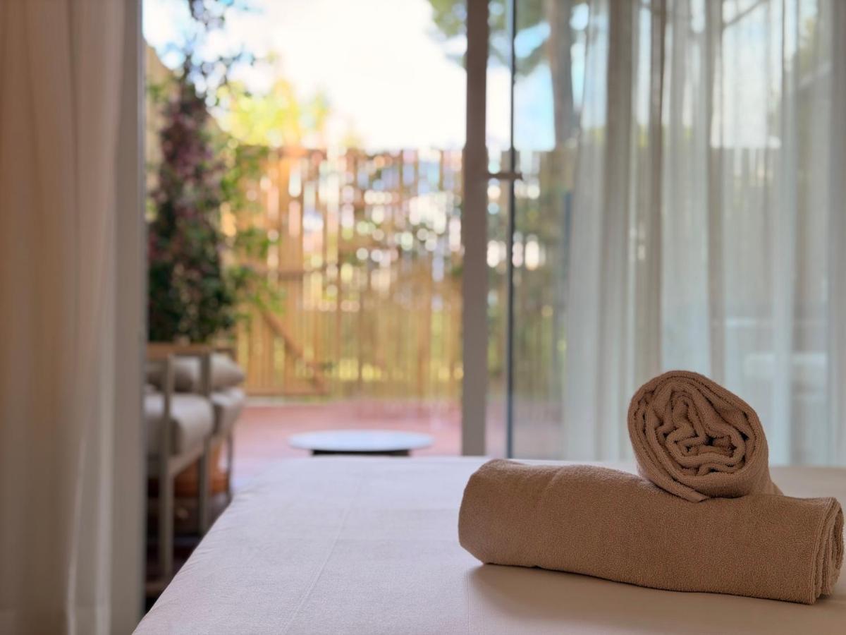 Beige rolled towel lies on white bed at pet-friendly Prinsotel La Pineda Hotel in Capdepera.