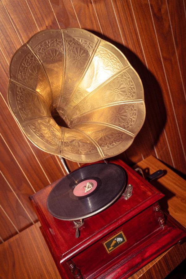 Brass engraved horn on red wooden phonograph with black vinyl record sits at pet-friendly 74 Otel in Antalya.