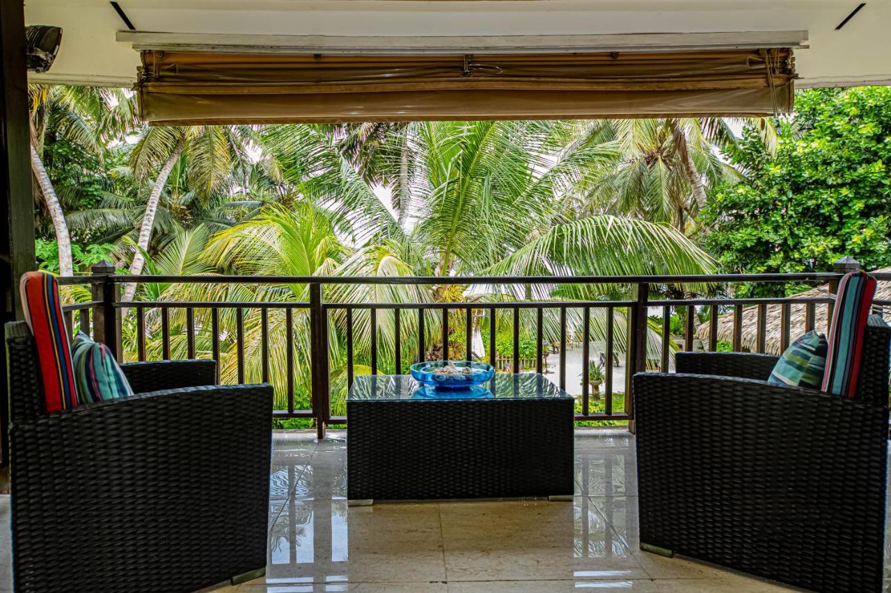 Two dark wicker chairs with striped cushions flank glass-top table at dog-friendly Villas des Alizes in Praslin Island.