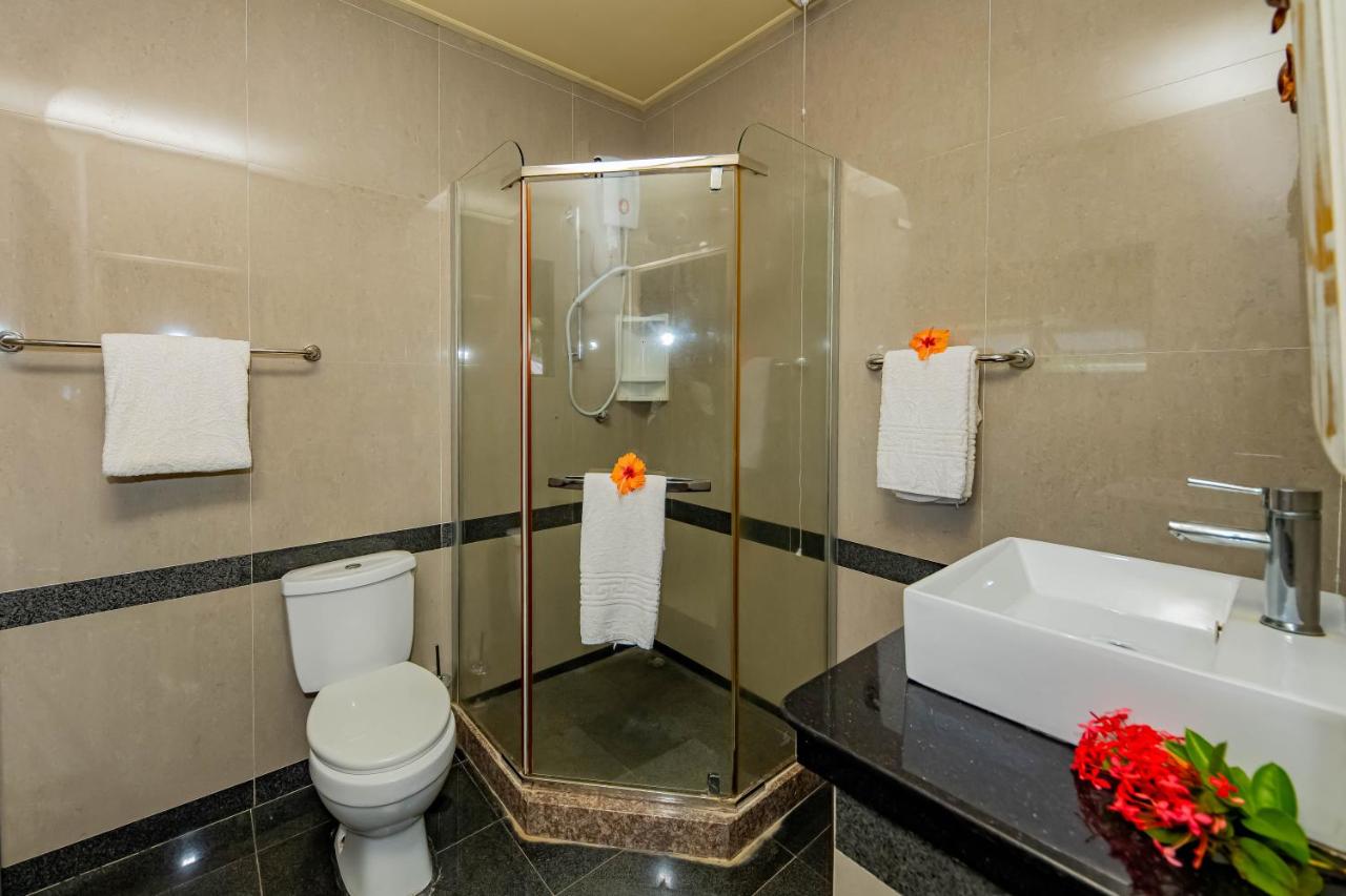 Beige tiled bathroom with glass shower and white towels is at dog-friendly Villas des Alizes in Praslin Island.