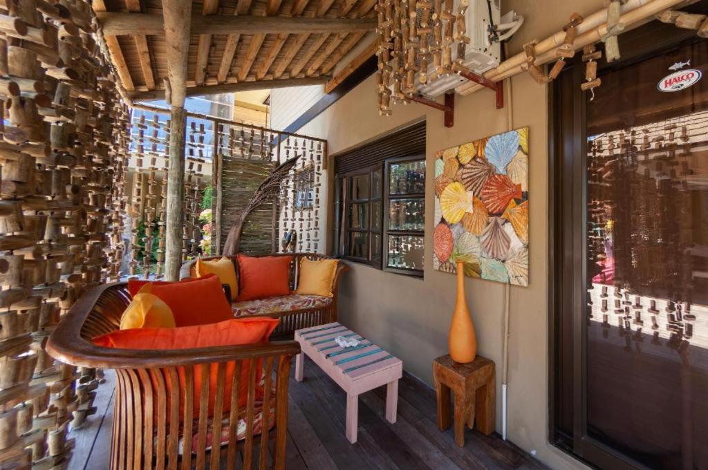 Brown wooden sofa with orange and yellow cushions sits at dog-friendly Villas des Alizes in Praslin Island.