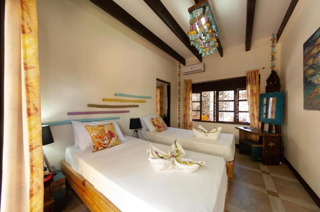 Two white twin beds with floral pillows are positioned at dog-friendly Villas des Alizes in Praslin Island.