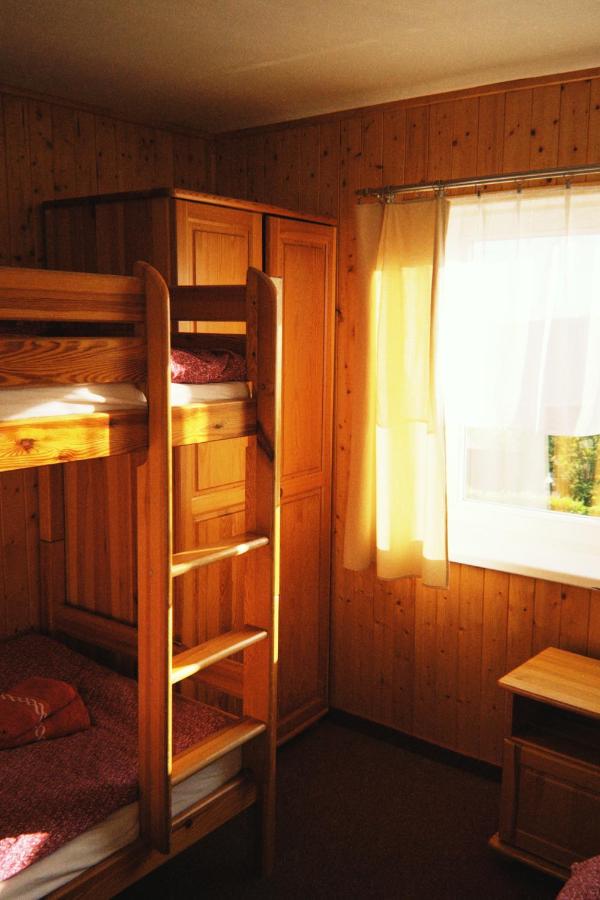 Wooden bunk bed with ladder and red blankets stands at pet-friendly Horská Chata Na pici in Benecko.
