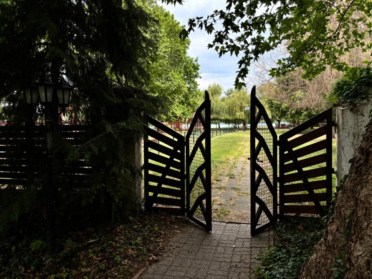 A pair of black wooden gates stands open at dog-friendly Grantek Üdülház in Balatonlelle.