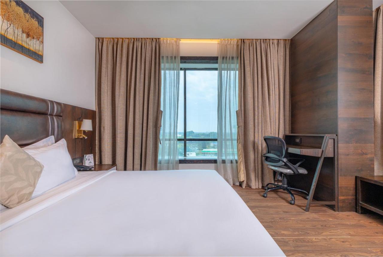 White bed with brown leather headboard sits at dog-friendly Econest Hotel in Tarapith.