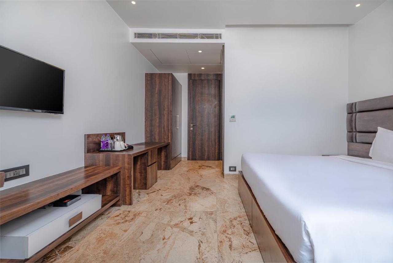 White-sheeted bed with brown upholstered headboard sits at pet-friendly Econest Hotel in Tarapith.