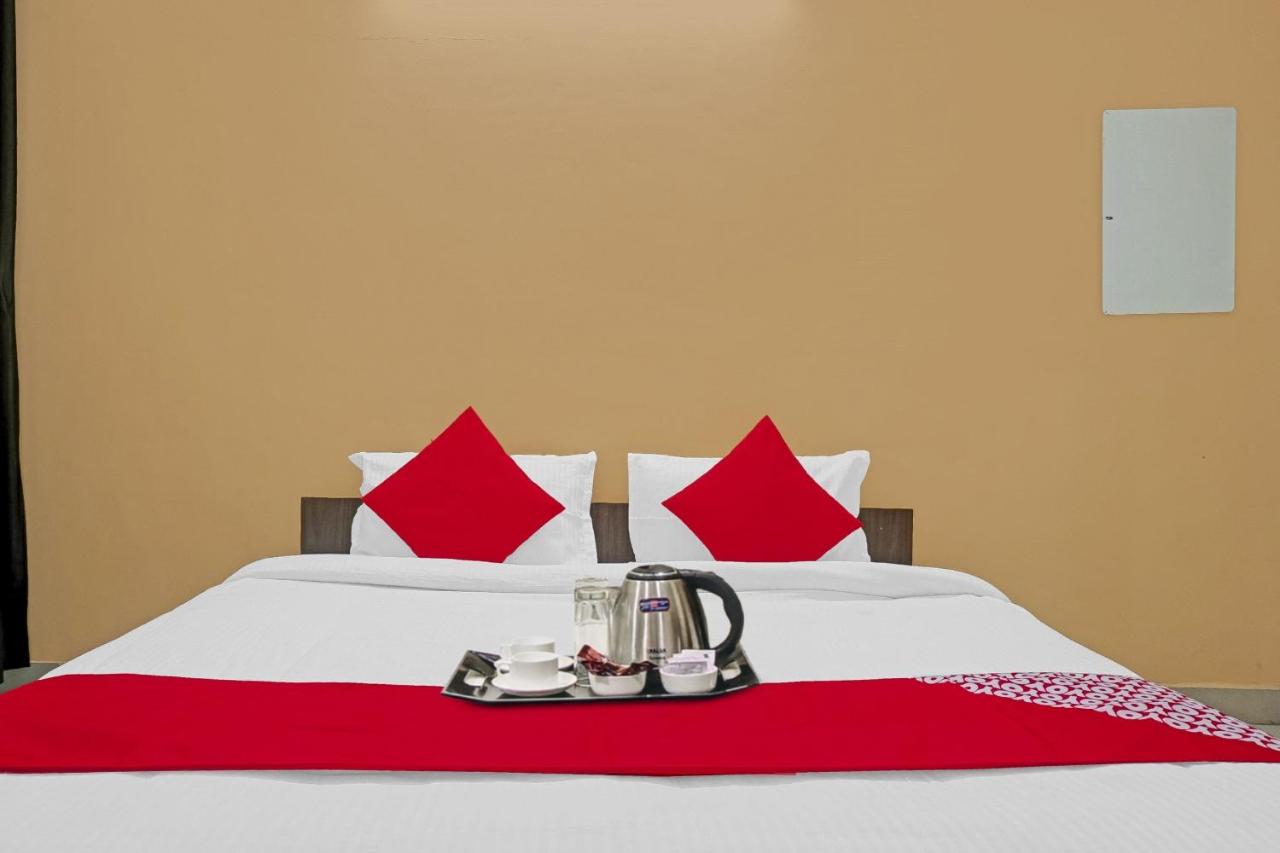 White bed with red pillows and kettle sits at dog-friendly Hotel O Sapphire Homes Stay in Hinjawadi.