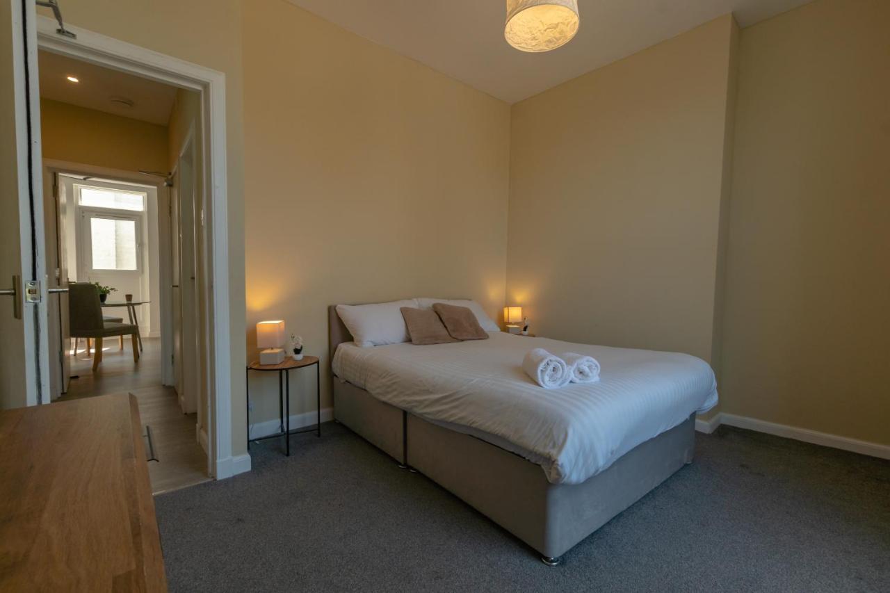 Beige bed with white linens and rolled towels rests at dog-friendly Edinburgh Shore Apartments in Edinburgh.