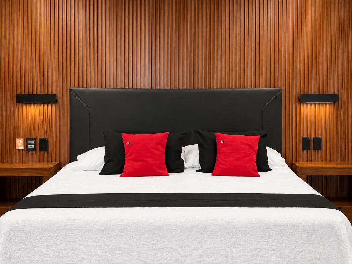The bed with white quilt, black headboard and red pillows sits at pet-friendly Vista Zacatlan Hotel in Zacatlán.