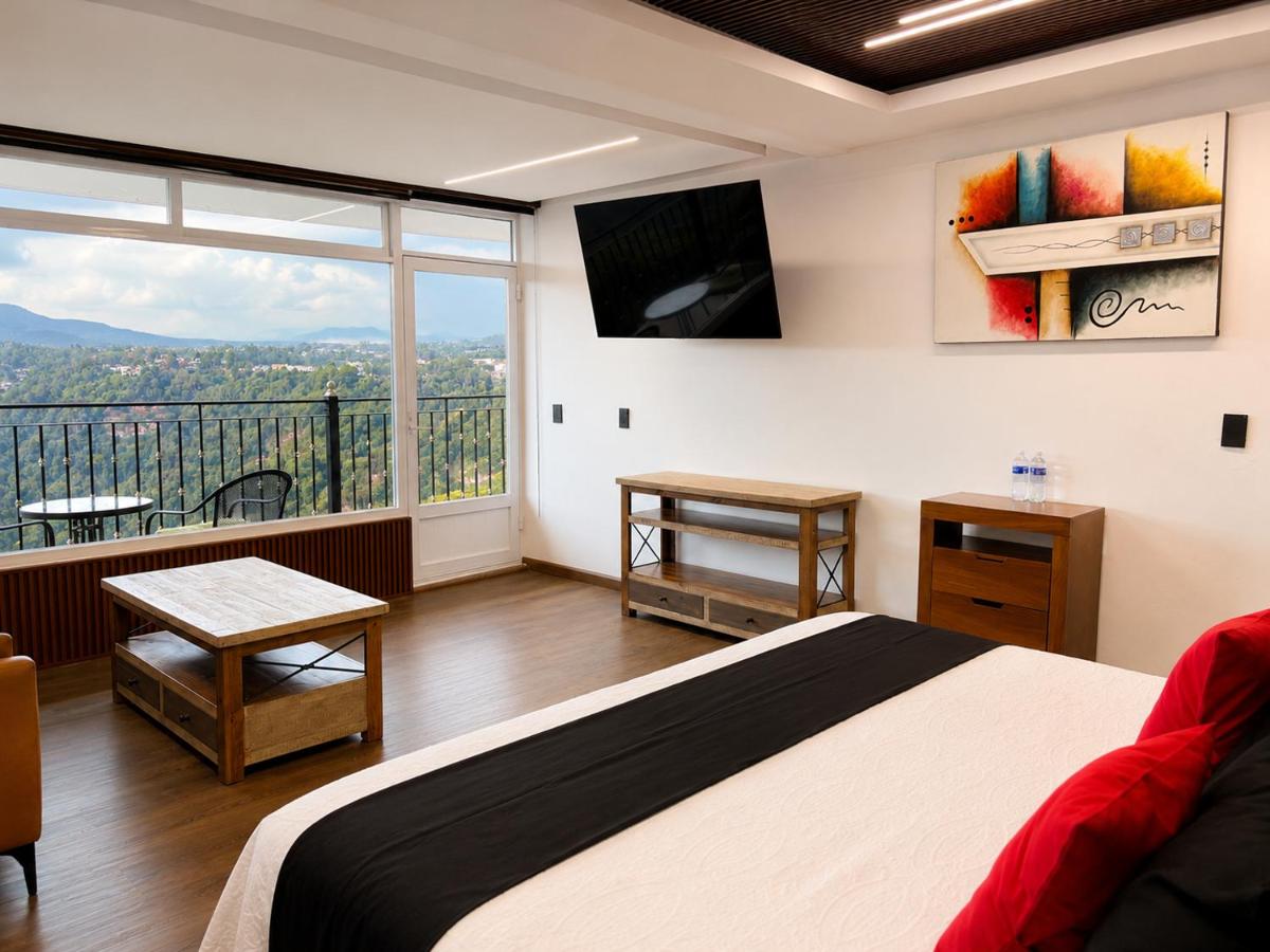 White bed with black runner and red pillows sits near balcony window at dog-friendly Vista Zacatlan Hotel in Zacatlán.