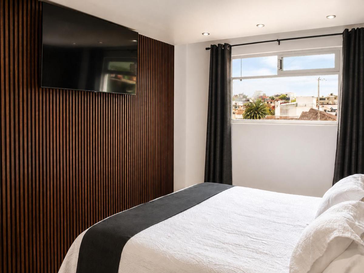 White bed with black runner is positioned at dog-friendly Vista Zacatlan Hotel in Zacatlán.