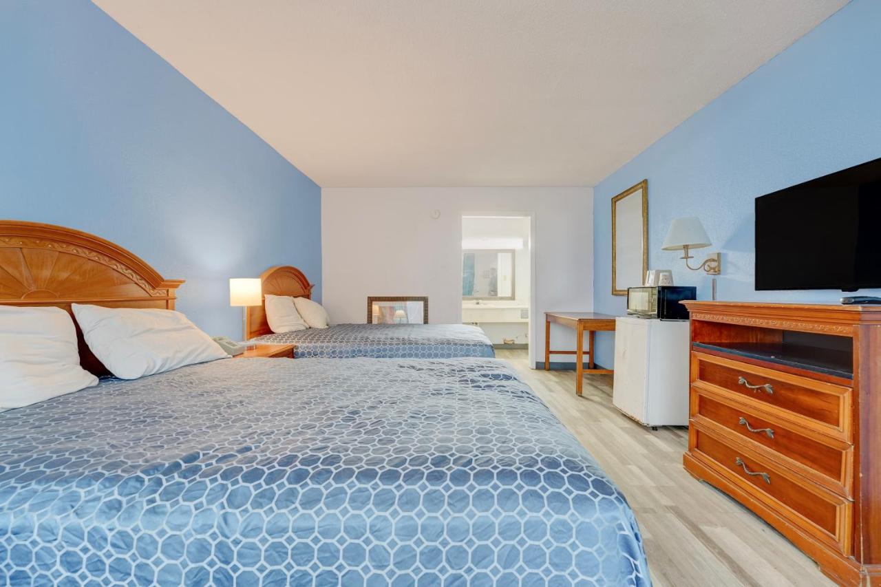 Two blue-patterned beds with wooden headboards sit at dog-friendly Ole South Inn Jackson I 40 TN in Denmark, TN.