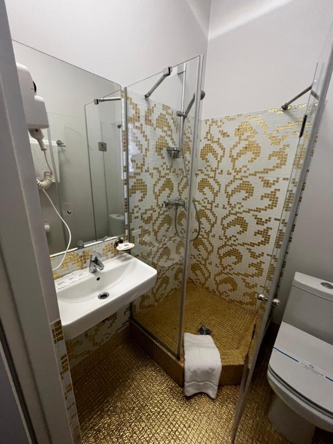 Gold mosaic-tiled shower stall stands at pet-friendly De Paris Hotel in Kyiv.