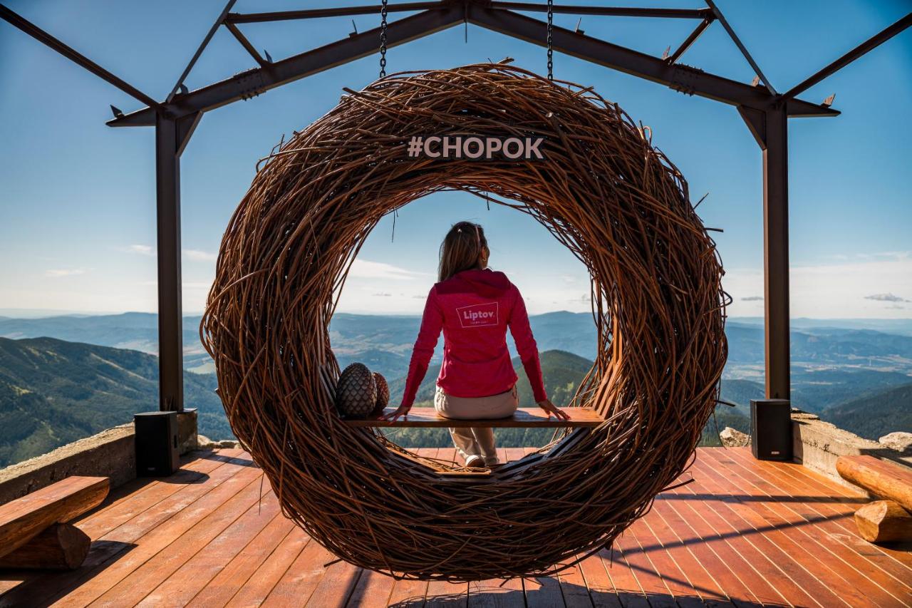 Woman in red Liptov jacket sits in wicker nest at dog-friendly Chalets Jasná Collection - Apartments in Demanovska Dolina.