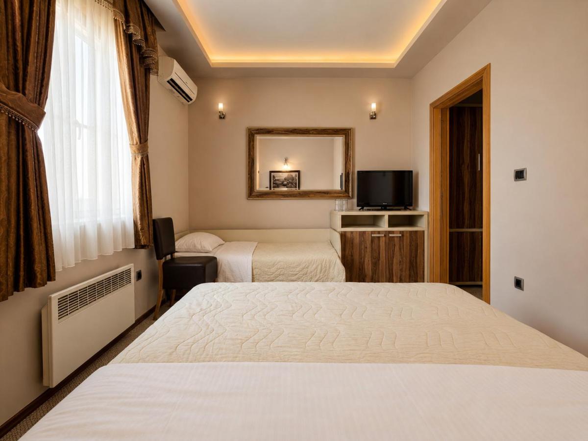 Beige bed with quilted cover sits at dog-friendly Hotel Intergaj Bijeljina in Bijeljina.