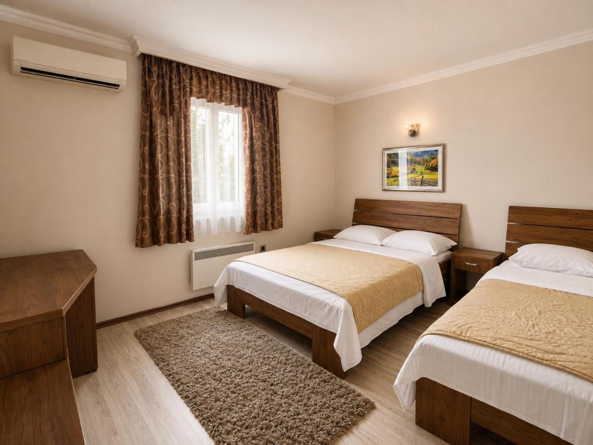 Two beds with beige bedspreads, white sheets and wooden headboards are positioned at dog-friendly Hotel Intergaj Bijeljina in Bijeljina.