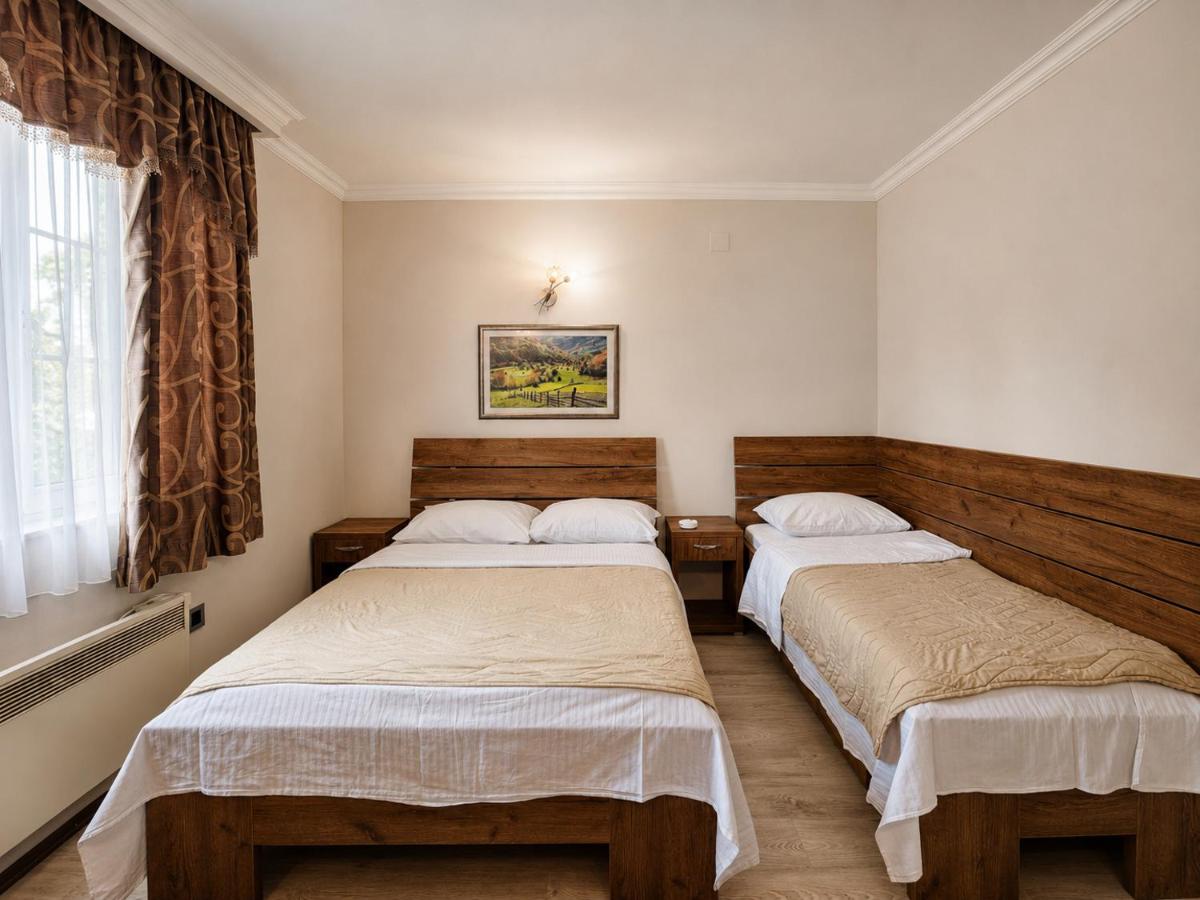 Two wooden beds with white sheets and beige blankets are at pet-friendly Hotel Intergaj Bijeljina in Bijeljina.